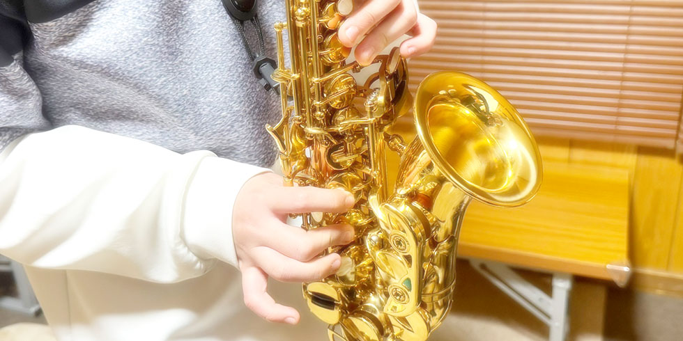 サックスの運指表を見ながら練習しているオリジナル写真